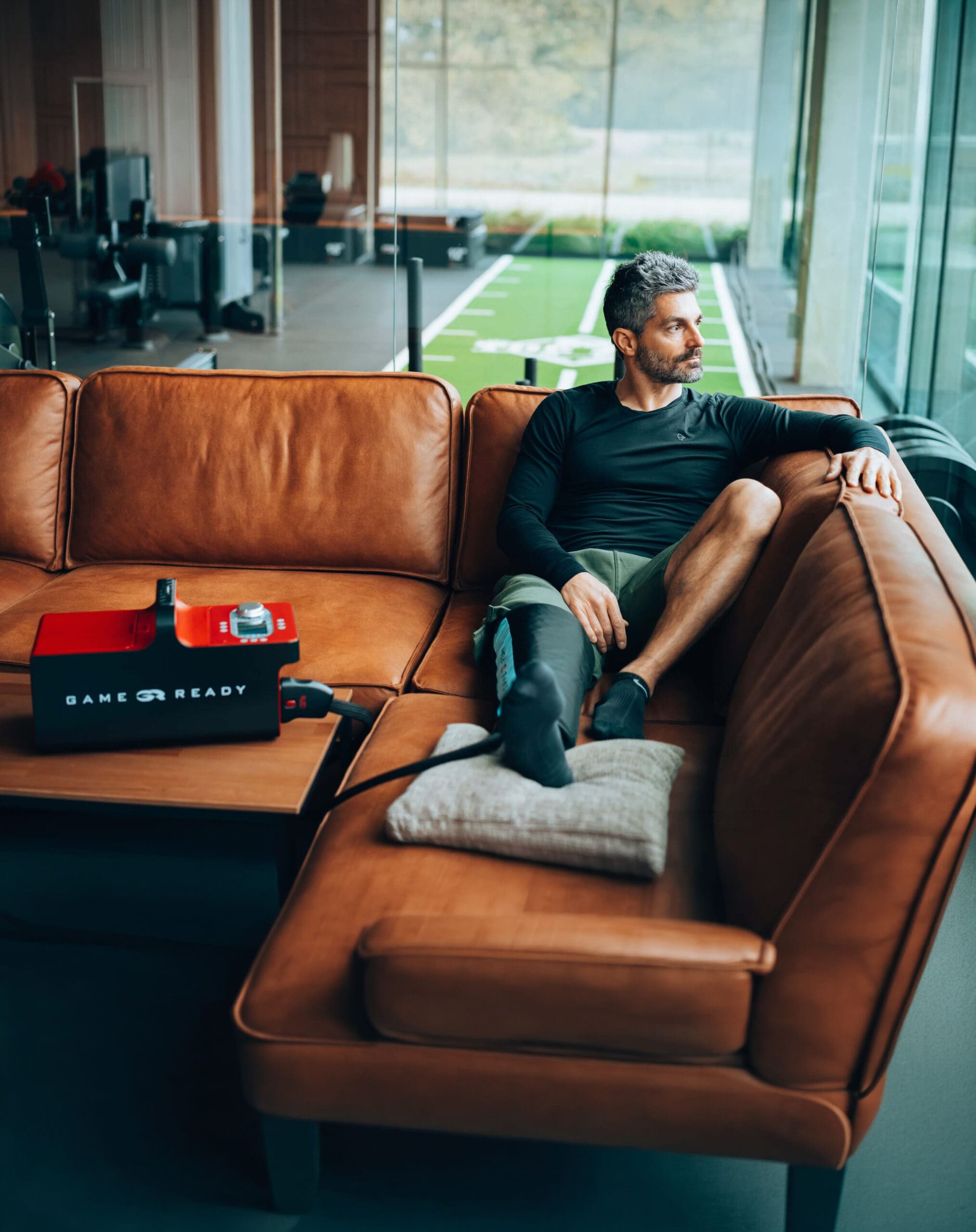 Game Ready-09 Mann sitzt auf Couch und kühlt das rechte Bein mit dem Game-Ready System.